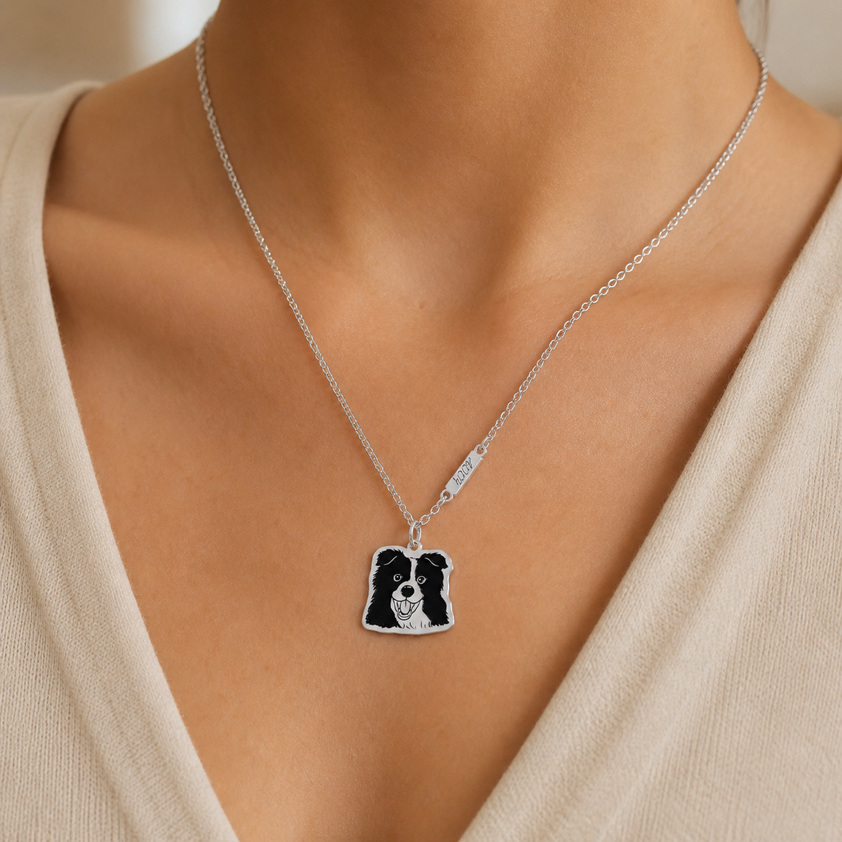 Styling illustration of a silver pet portrait necklace worn with a cream top